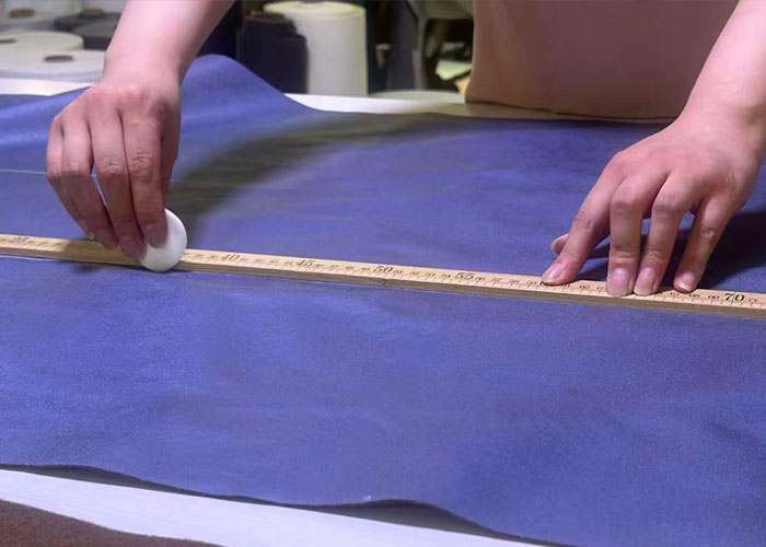 Hands measuring purple upholstery fabric with a tape measure