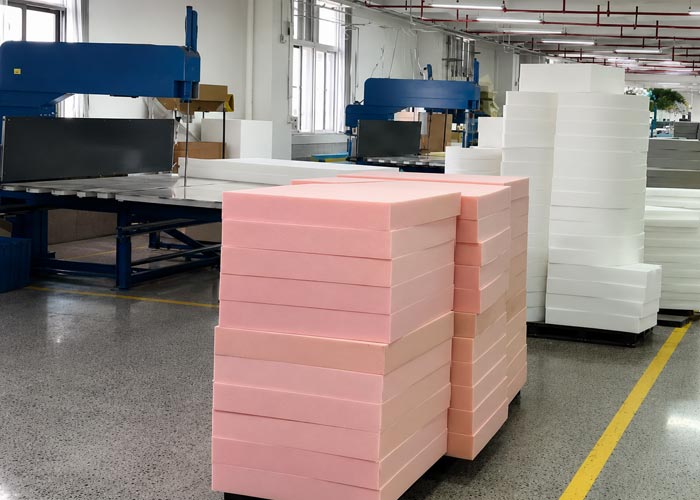 Stacks of pink and white foam blocks beside cutting equipment