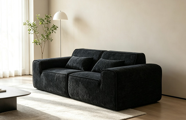 Black sofa with wide armrests in a bright living room