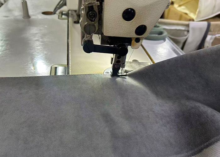 Industrial sewing machine stitching gray upholstery fabric